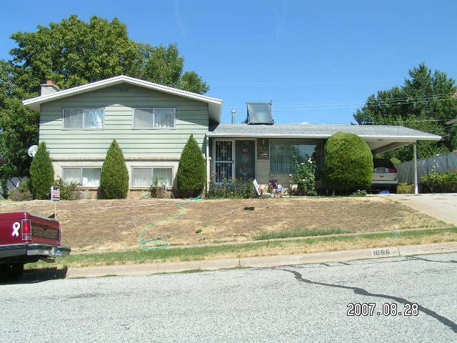 A green house with a front lawn of dirt.
